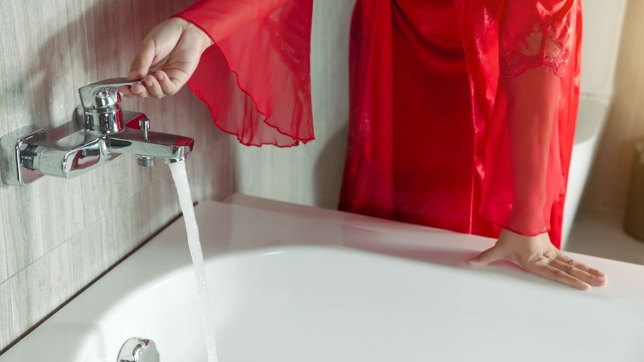 mulher com robe vermelho enchendo banheira